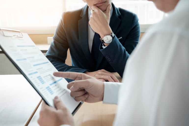 business man interviewer looking skeptical while listening to an asian female interview