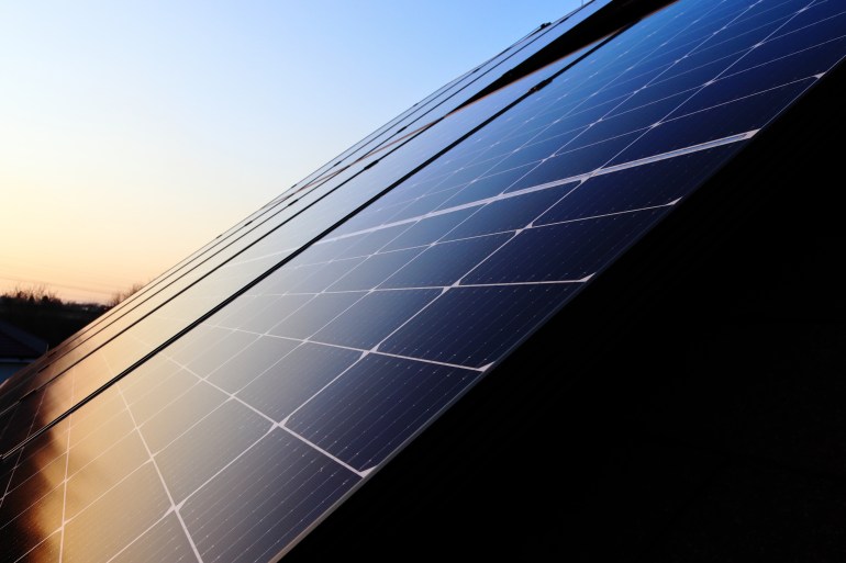 The roof of the house is covered with photovoltaic panels. Sunset. Green energy. Photovoltaic power plant on the roof of the house.