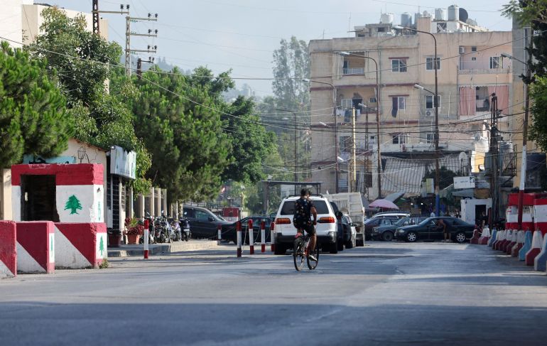 A person rides a bicycle near the entrance of Ain el-Hilweh Palestinian refugee camp, in Sidon