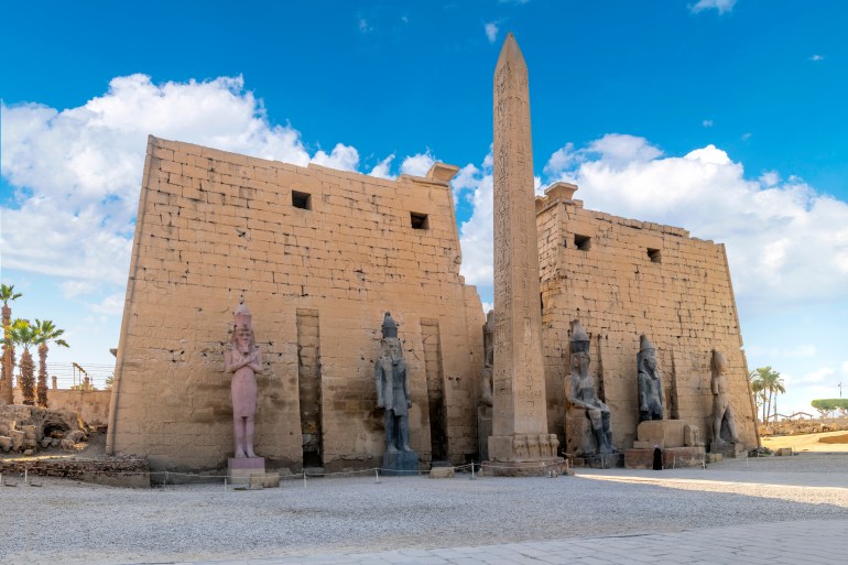 Luxor, Egypt - November 22 2022: The entrance to the ancient Egyptian Luxor Temple with statues of Rameses II and the pylon obelisk in front.