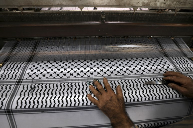 A worker cuts excess strings at a textile factory producing the Palestinian Keffiyeh scarf in the occupied West Bank city of Hebron on November 20, 2023. (Photo by HAZEM BADER / AFP)