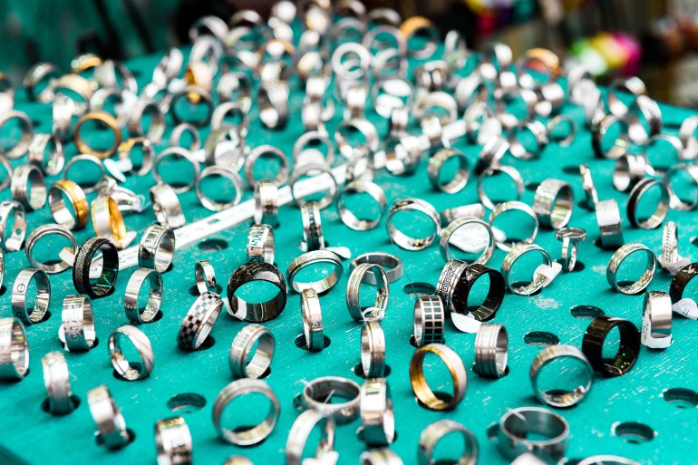 Display with different designs of handmade silver rings on green stand. Close-up of handmade jewelry shop window display.