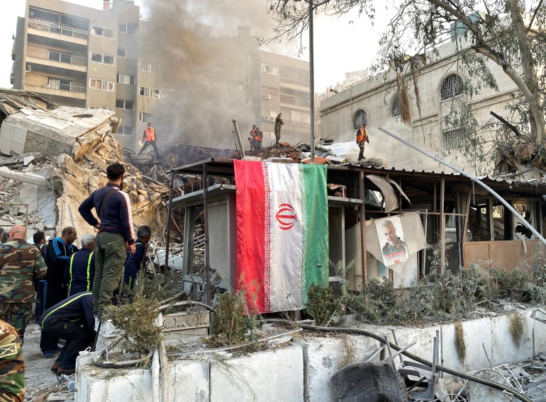 An Iranian flag hangs as smoke rises after what the Iranian media said was an Israeli strike on a building close to the Iranian embassy in Damascus, Syria April 1, 2024. REUTERS/Firas Makdesi