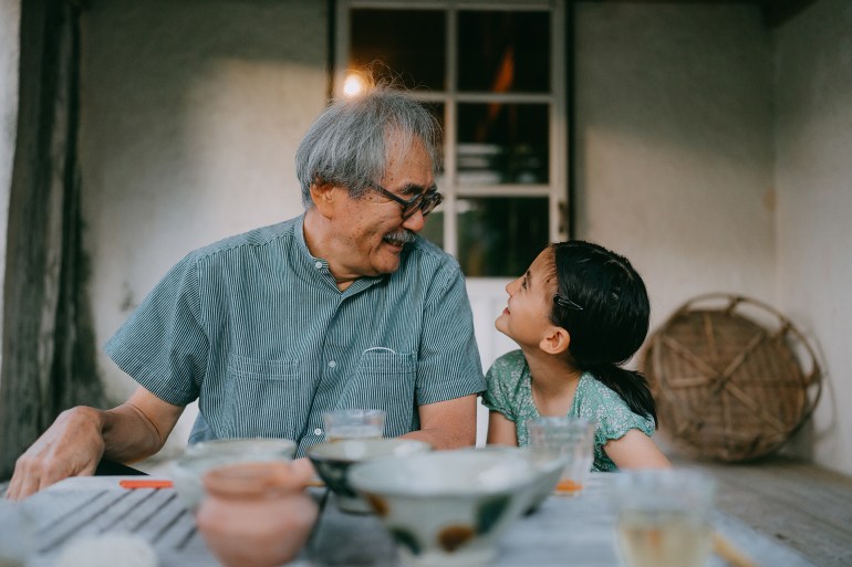 Cheerful grandfather and his granddaughter having a good time on patio