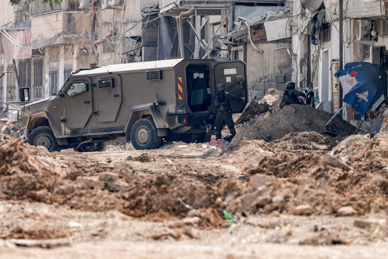 Israeli soldiers disembark off an armoured vehicle as they take position during an army operation in Tulkarm in the north of the occupied West Bank on August 29, 2024. - Israel on August 28 launched a large-scale operation in the occupied West Bank where the military said it killed Palestinian fighters, as the nearly 11-month-old Gaza war showed no signs of abating. (Photo by Jaafar ASHTIYEH / AFP)