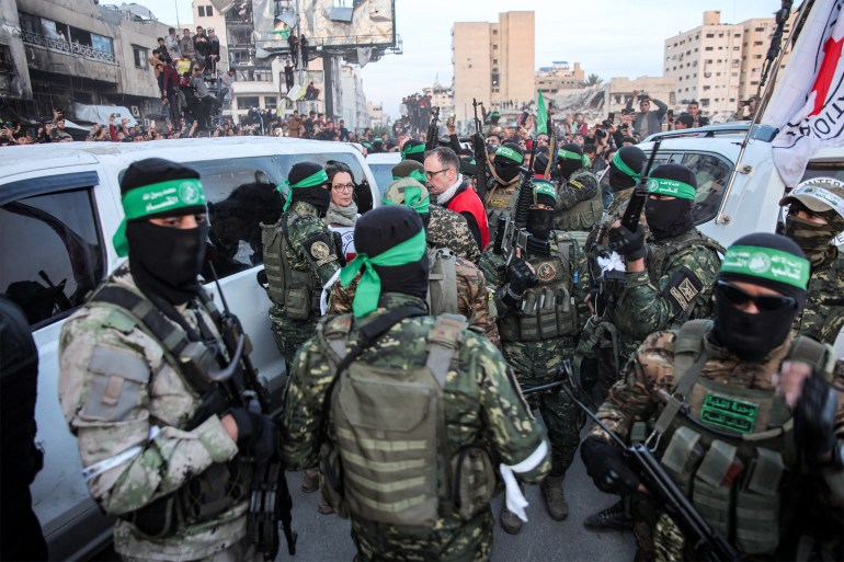 Members of the International Committee of the Red Cross (ICRC) speak with fighters of the Ezzedine al-Qassam Brigades, Hamas's armed wing, in Saraya Square in western Gaza City on January 19, 2025. The Israeli military said the Red Cross had confirmed the handover of three hostages on January 19, the first to be released as part of a ceasefire deal with Hamas. The Hostage and Missing Families Forum campaign group had identified the three women set to be released as Emily Damari, Romi Gonen and Doron Steinbrecher, seized during Hamas's October 7, 2023 attack that triggered the war. (Photo by Omar AL-QATTAA / AFP)