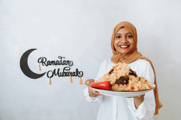 Woman in Brown Hijab Holding a Plate with Food