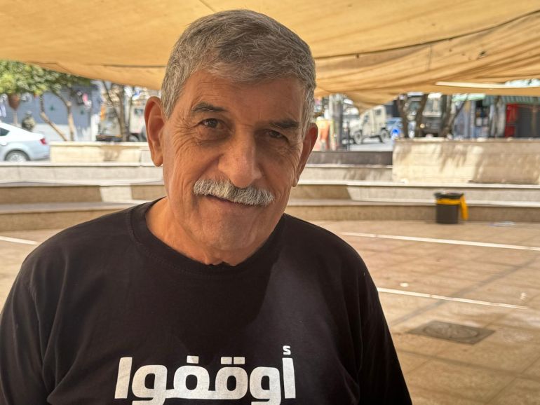 5 - فلسطين،البيرة، الجزيرة نت. عمر عساف في ساحة مركز بلدية البيرة ومن خلفه جيبات الاحتلال خلال اقتحامها وسط المدينة.