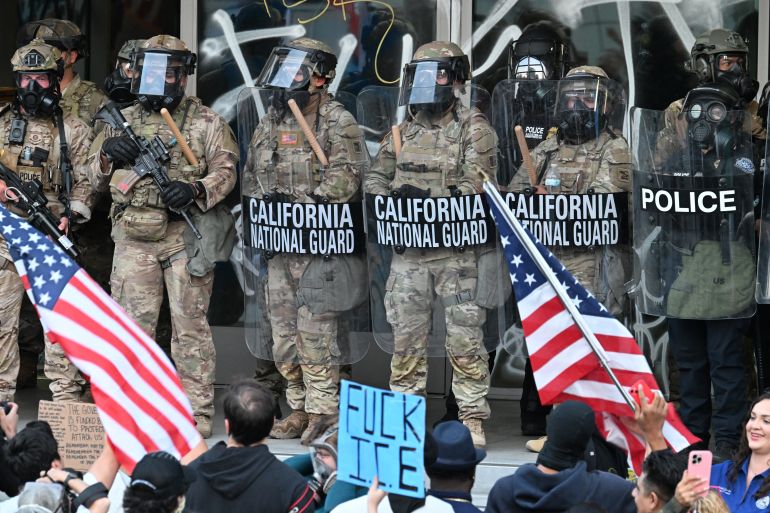 California National Guard and US Customs and Border Protection watch demonstrators gather in front the Federal Building before curfew goes in effect following days of protests in response to federal immigration operations in Los Angeles on June 10, 2025.